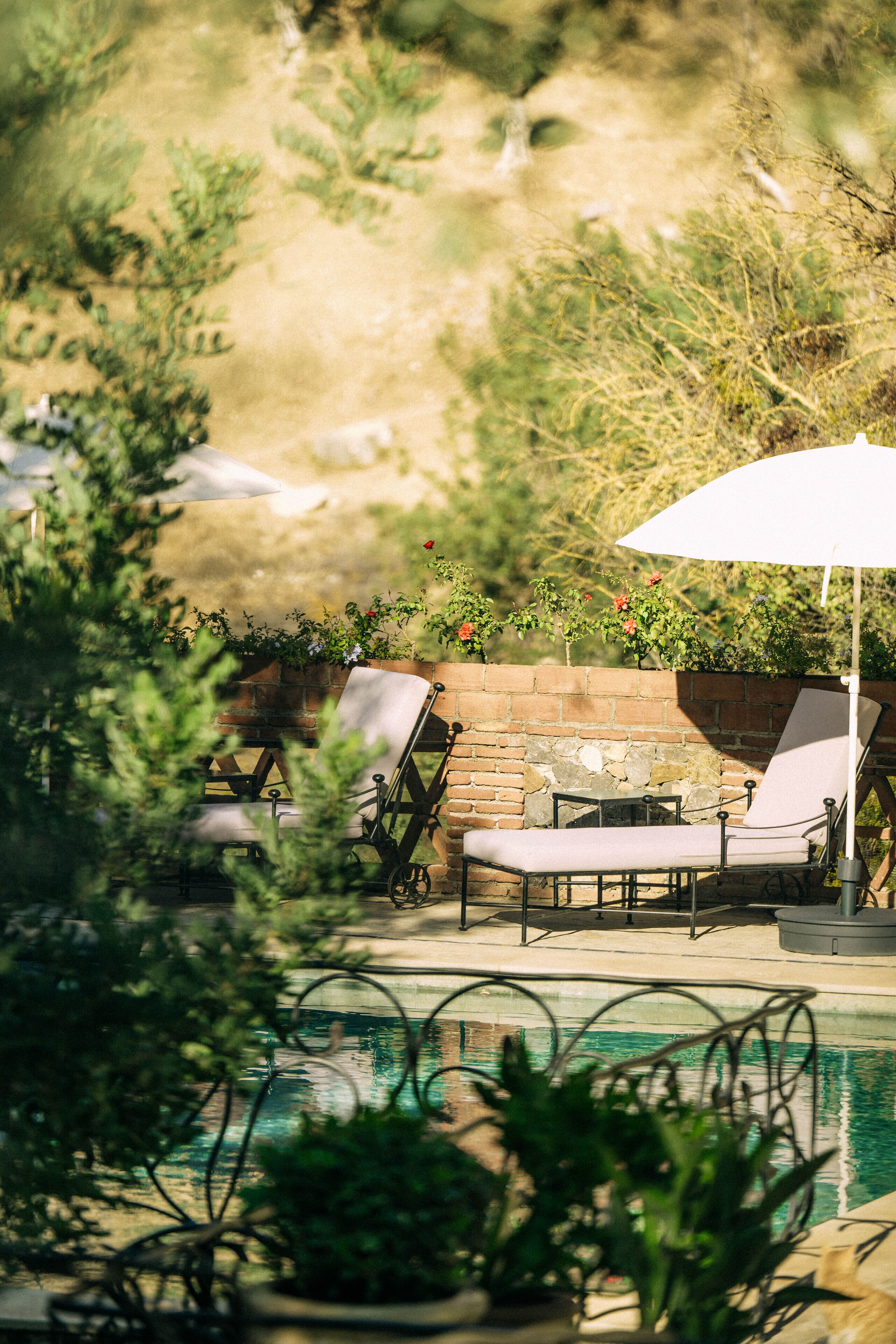 A poolside area with lounge chairs and a brick wall.
