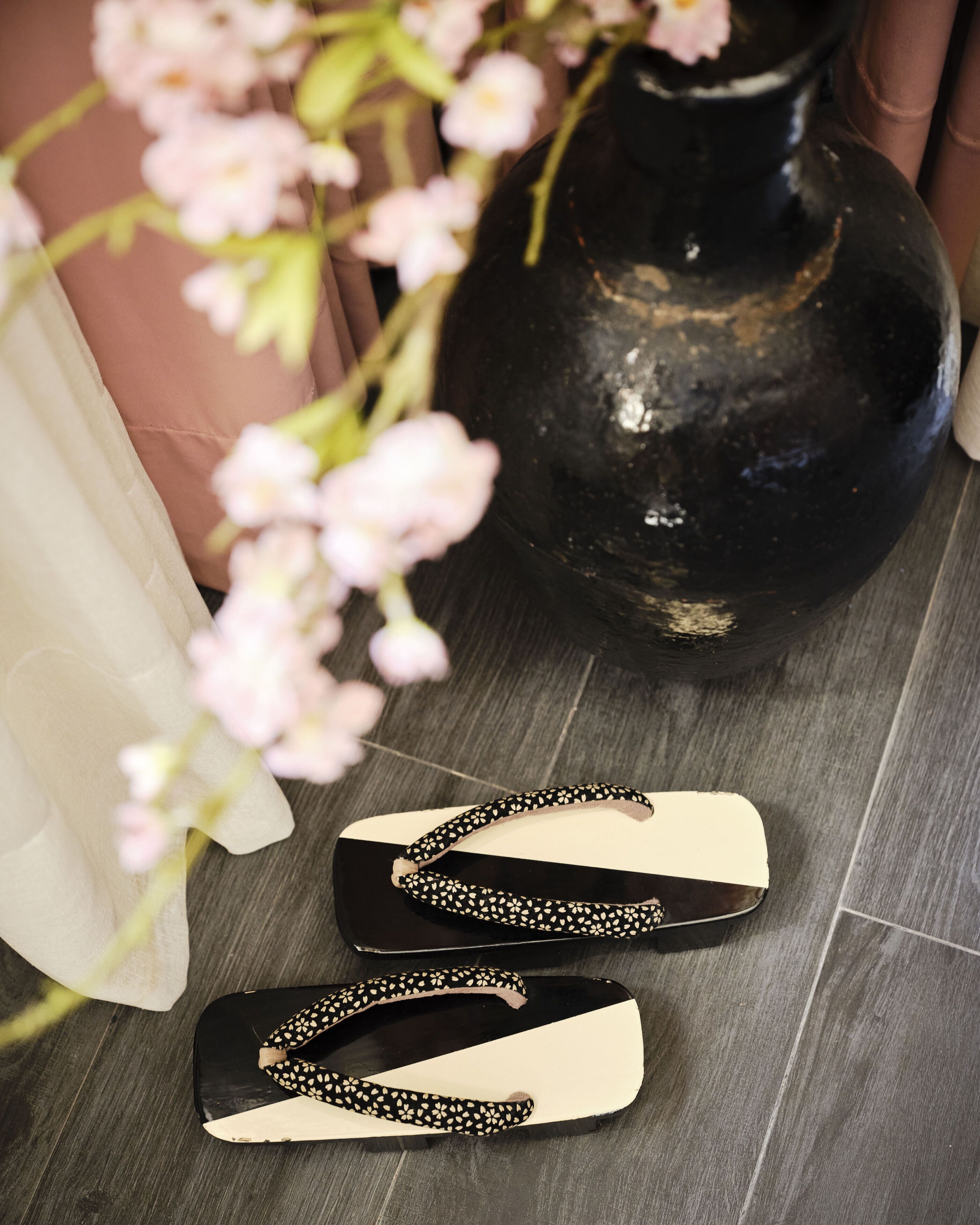Un par de sandalias blancas y negras con un estampado floral sobre un piso de madera.