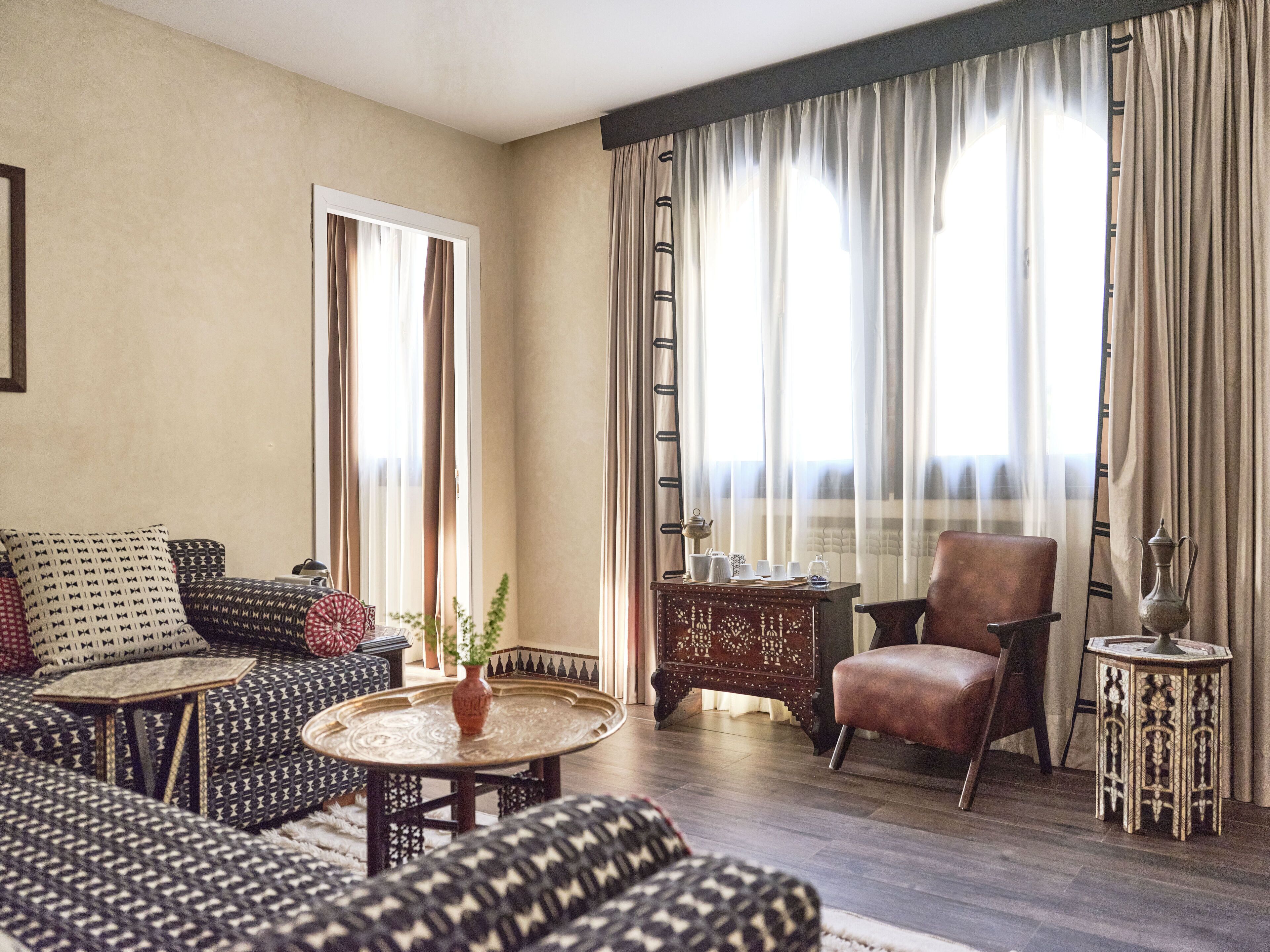 Un salon comprenant un canapé, un fauteuil et une petite table sur laquelle est posé un vase.