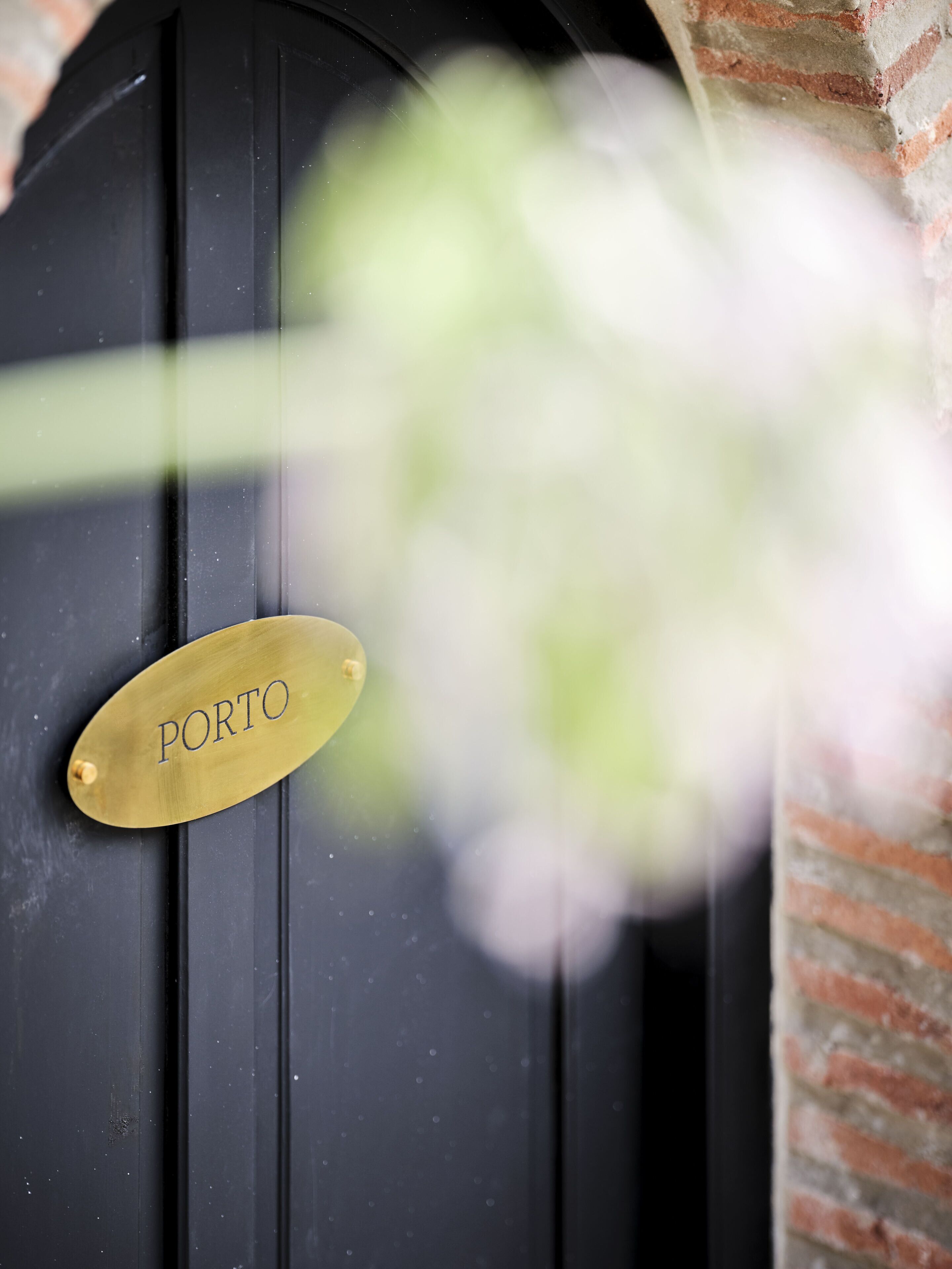 Una puerta negra con una placa de latón que dice 'PORTO'.