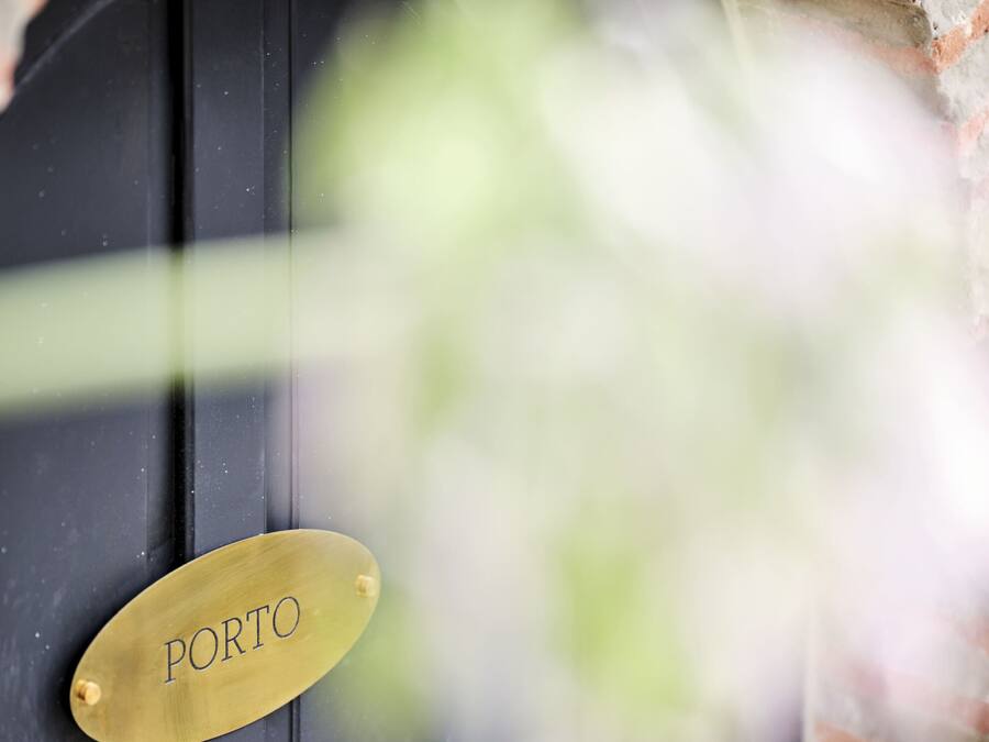 Una puerta negra con una placa de latón que dice 'PORTO'.