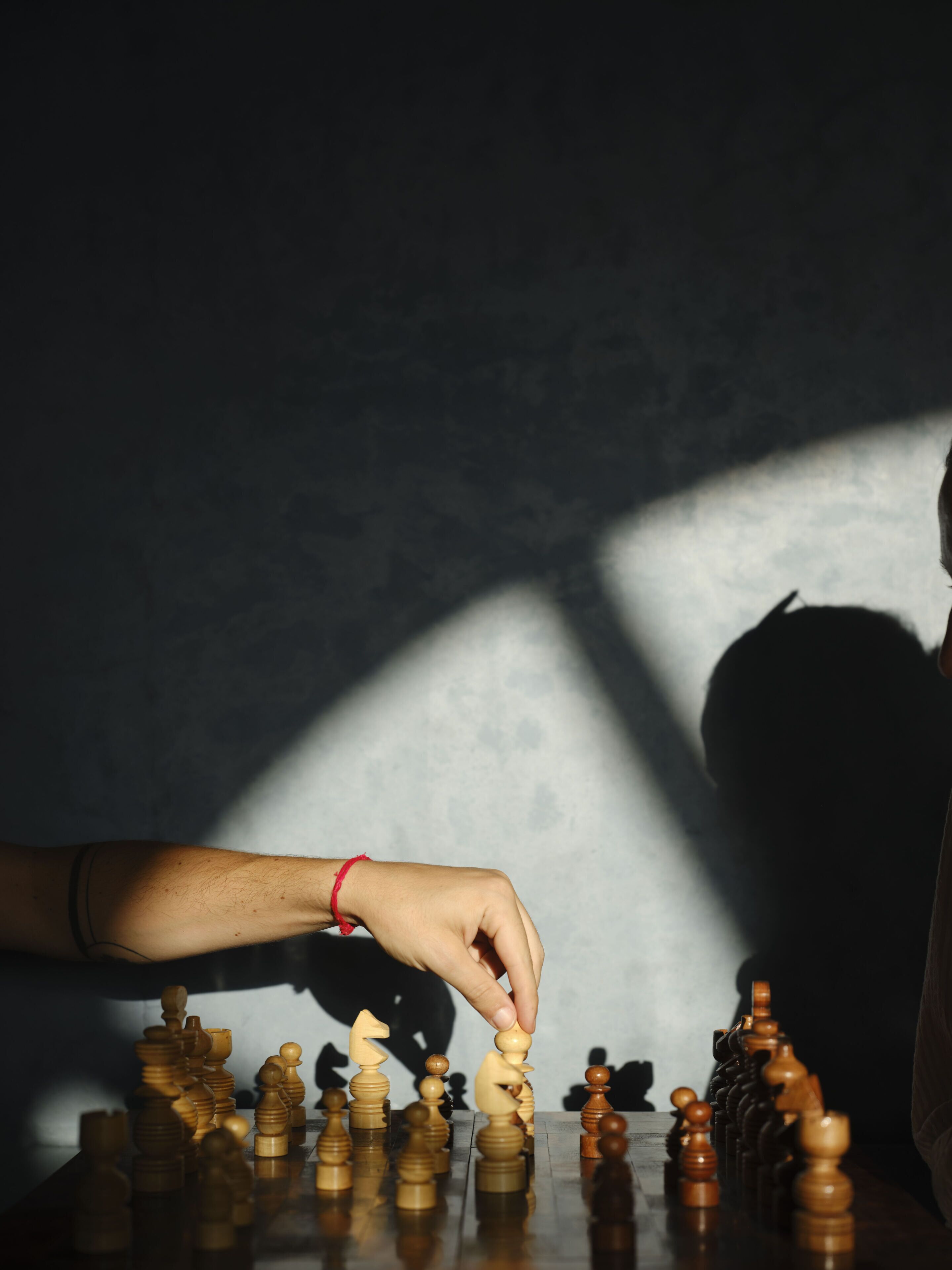 A hand placing a chess piece on a board.