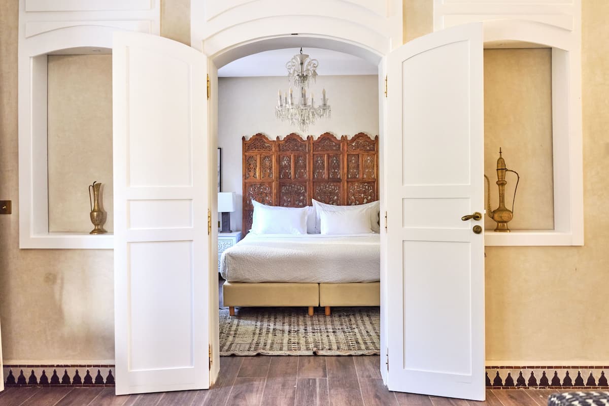 A bedroom with a large bed, a chandelier, and a decorative headboard.