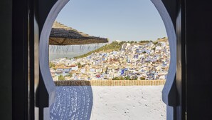 Vista a través de un ventanal arqueado de una zona urbana densamente poblada, con edificios muy cercanos en una ladera.