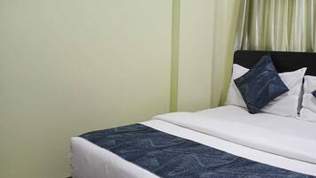 Quarto com cama, cabeceira, janela com cortinas e três quadros na parede.