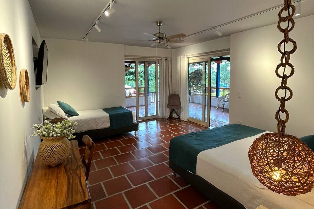 Un dormitorio moderno con dos camas, una mesa de madera y una lámpara colgante.
