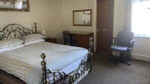 A hotel room with a bed, a desk, a chair, a mirror, and a door. - SOUTH LAKES TOWN CENTRE HOUSE (Barrow-in-Furness)