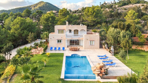 Een villa in mediterrane stijl met een zwembad, terras en een weelderige tuin.