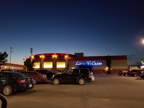 Un estacionamiento con varios autos estacionados frente a un edificio con un letrero de neón que dice 'LIVIN' SKY Casino'.