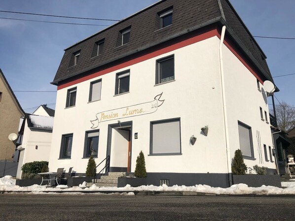 A white building with a red trim and a sign that reads "Pension Lumière 2012". - Pension Lume (Oberraden)