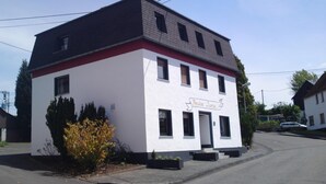 A two-story building with a white facade and a red trim. The sign on the building reads "Pension Lume." - Pension Lume (Oberraden)