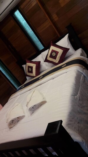 A bed with a white bedspread, two decorative pillows, and a folded white towel. - Pun Na Homestay Bangsai (Bang Sai)