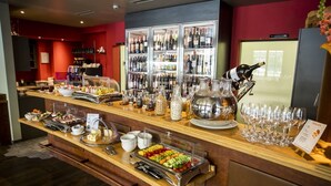 A buffet setup with various food items, a wine refrigerator, and a selection of wine glasses.