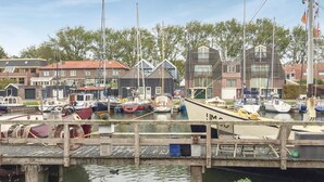 Een jachthaven met afgemeerde boten, een houten steiger en woongebouwen op de achtergrond.