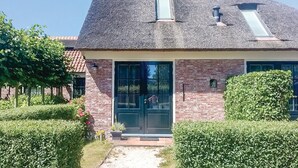 Een huis met een steil dak, een bakstenen gevel en een voordeur met een ruit.