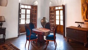 Una habitación con techo de madera, una mesa redonda con sillas y un cuadro grande en la pared.