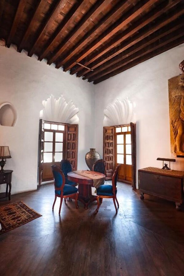 Une pièce avec un plafond en bois, une table ronde entourée de chaises et un grand tableau accroché au mur.