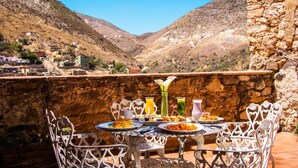 Una mesa de comedor con sillas dispuestas al aire libre, con vistas a un paisaje montañoso.