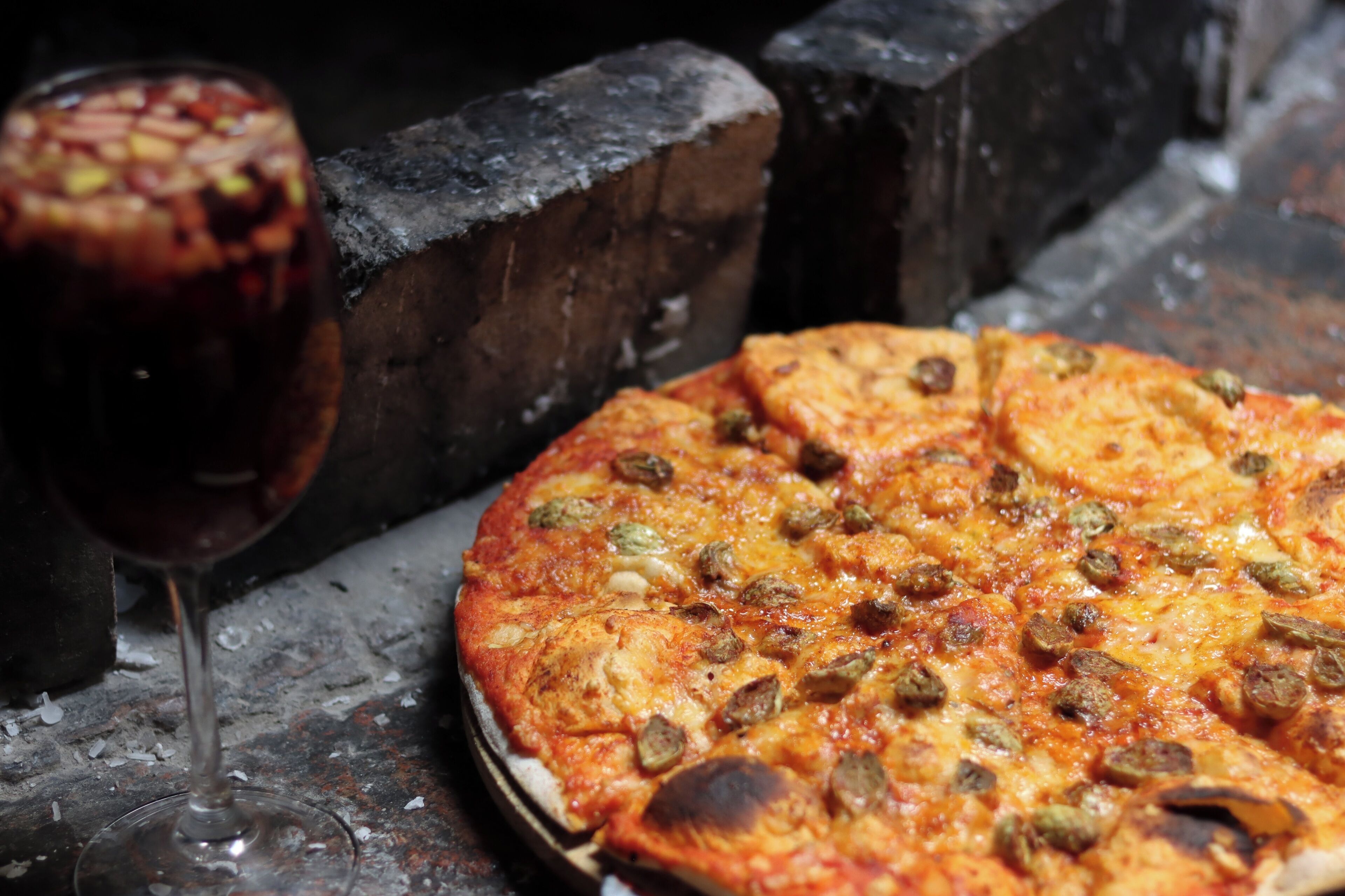 A pizza with sausage toppings on a wooden surface.