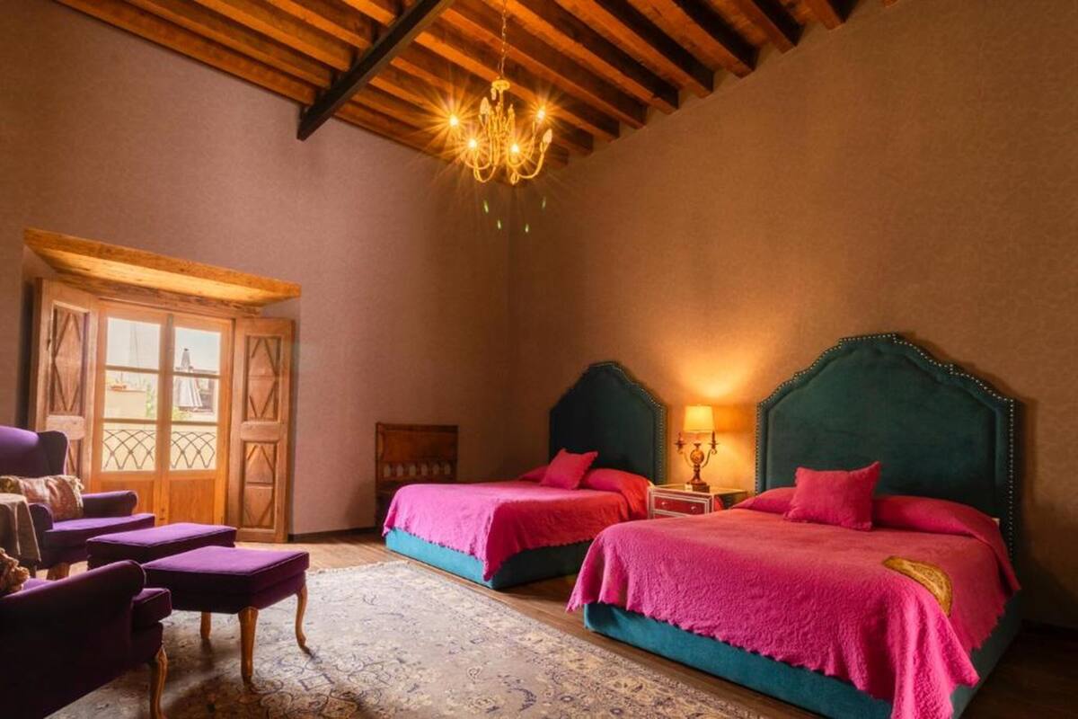 Une chambre avec deux lits, un lustre et une porte en bois.
