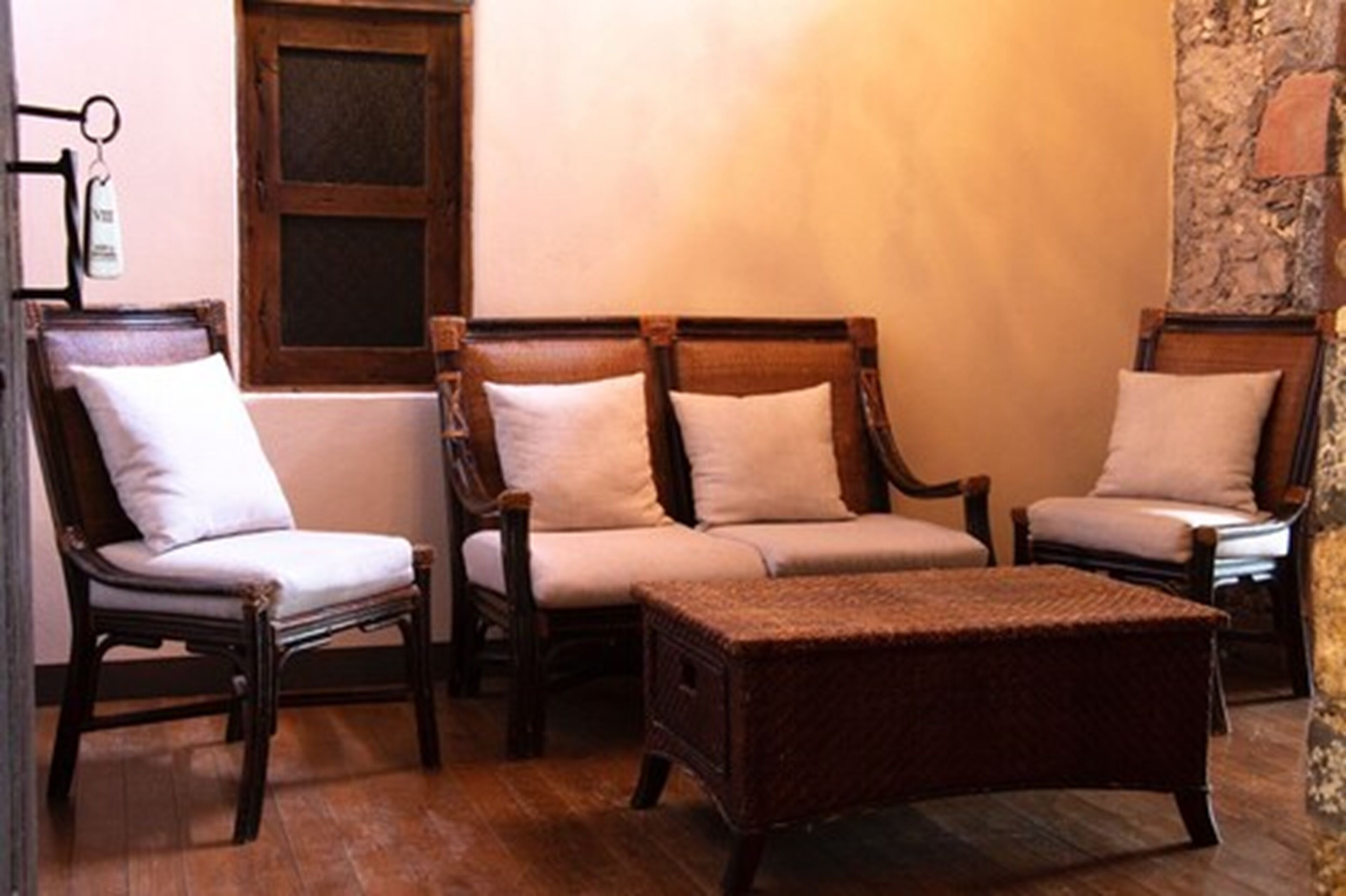 A room with three wooden chairs and a woven ottoman.