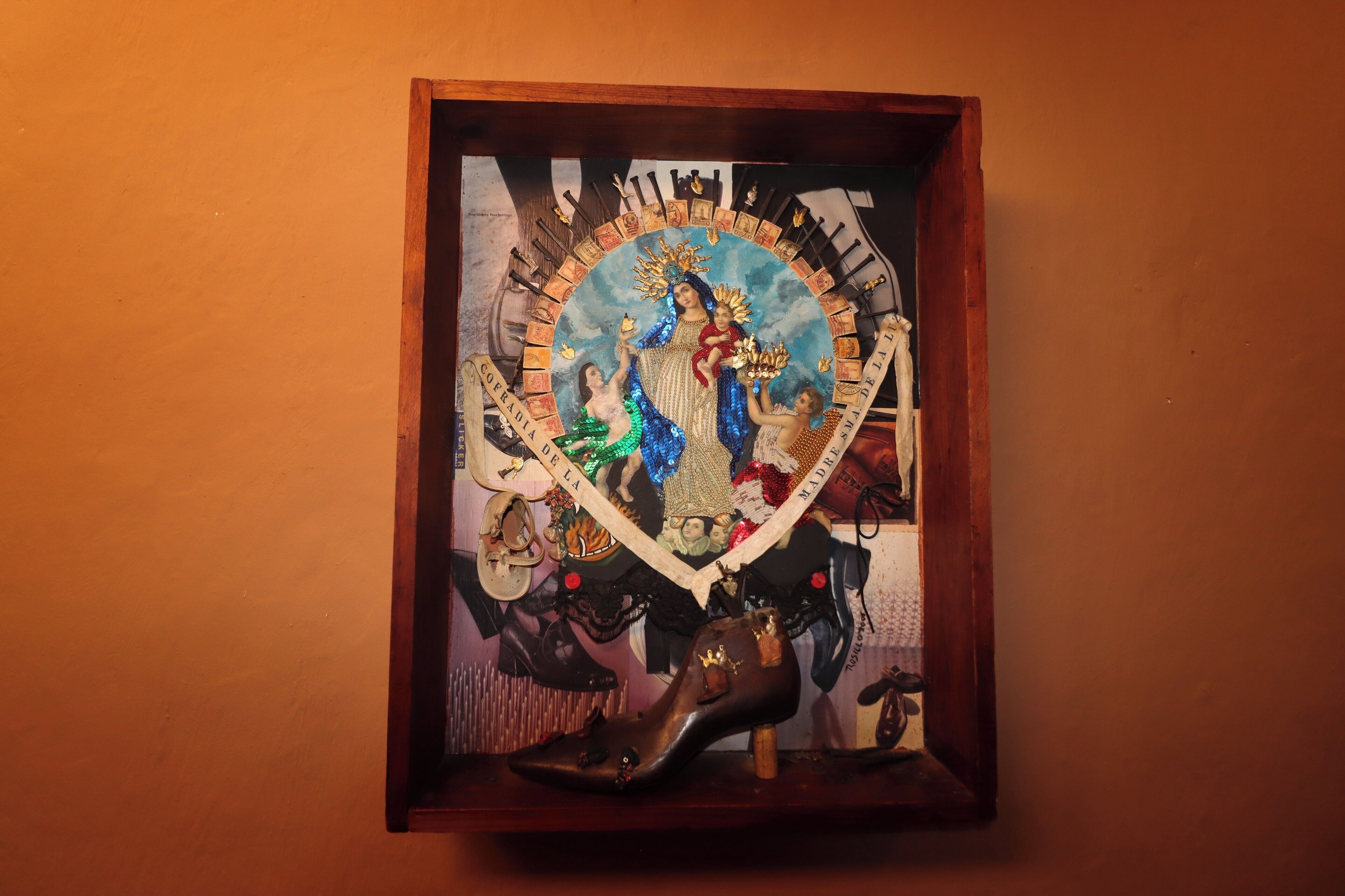 A framed artwork with a religious figure, surrounded by various objects including a shoe and a small bottle.