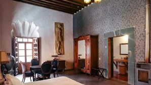 Un dormitorio con una cama grande, un candelabro, una chimenea y vistas al exterior.