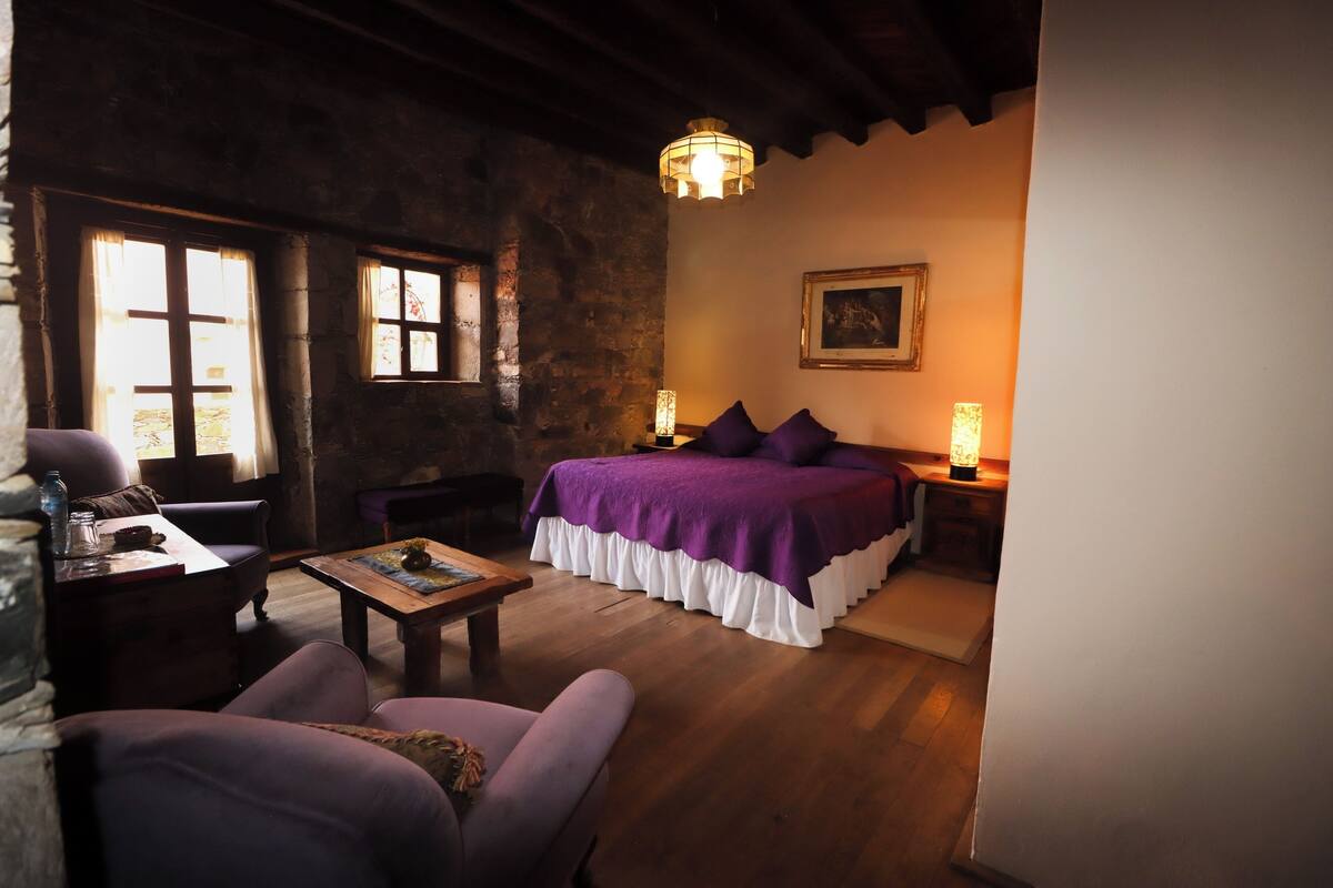 Une pièce confortable avec un lit, une table en bois, une chaise et une lampe.