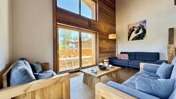 Un intérieur en bois avec un canapé, une table et une vue sur un bâtiment en bois à l’extérieur.