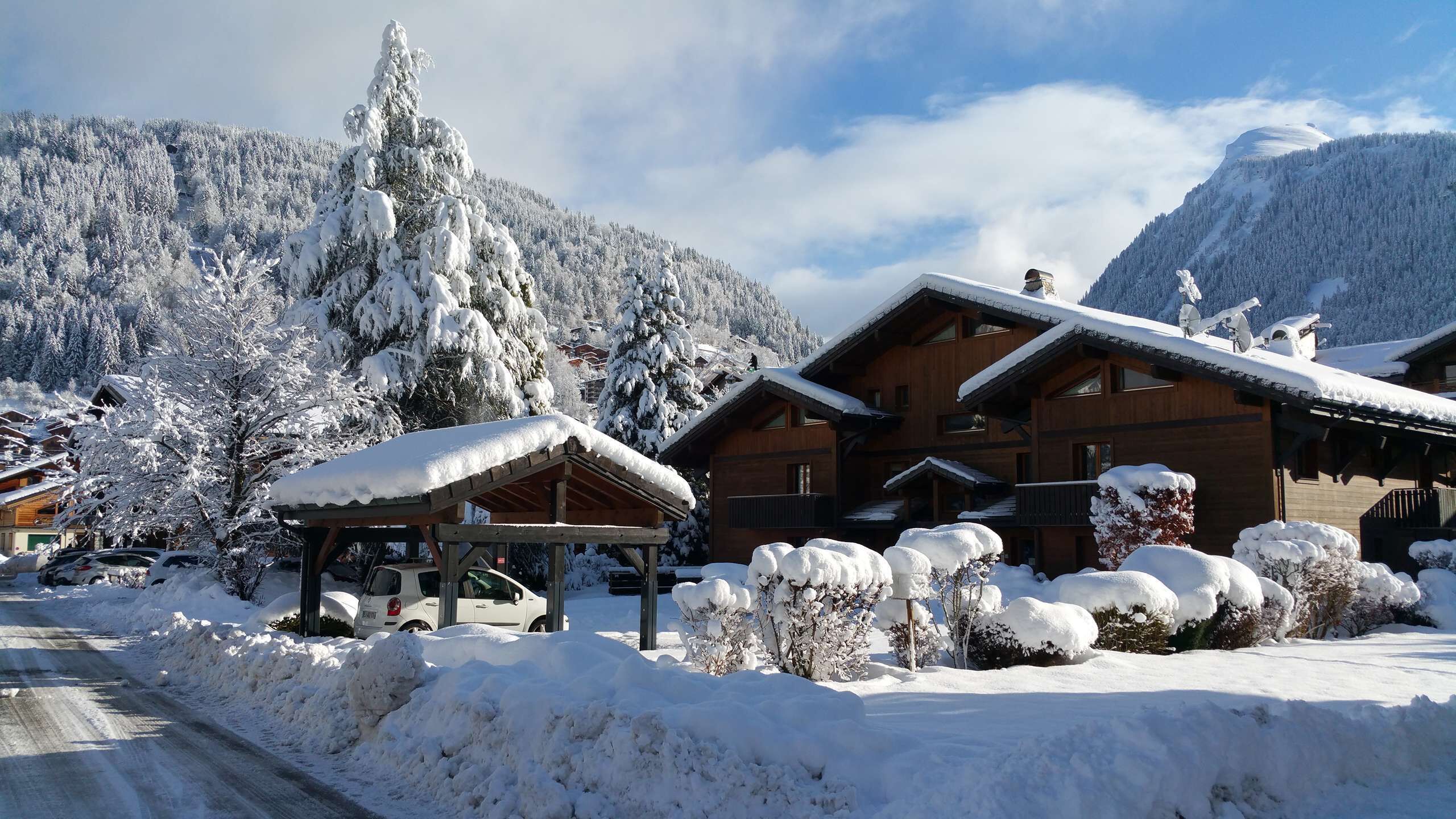 Una cabaña de madera con un porche cubierto y alrededores nevados.