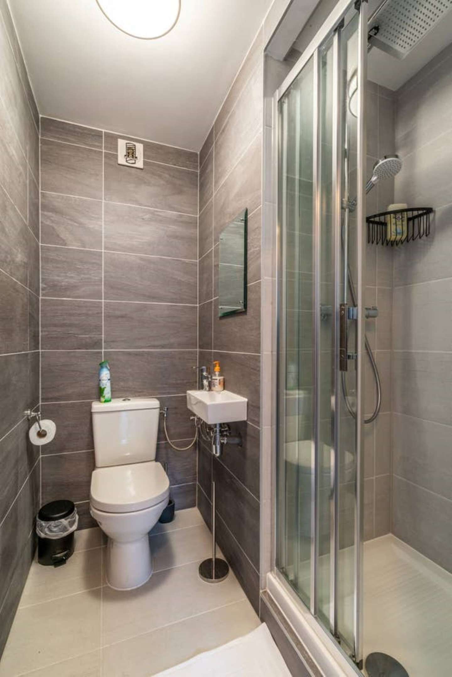 A modern bathroom with a toilet, sink, and glass-enclosed shower.