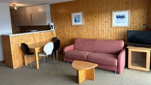 A compact living space with a kitchenette, a sofa, a coffee table, and a TV. - Diablerets D 012 -MOUNTAIN studio 4 pers (Veysonnaz)