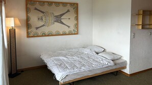 A bedroom with a bed, a floor lamp, and a wall art piece. - Diablerets D 012 -MOUNTAIN studio 4 pers (Veysonnaz)
