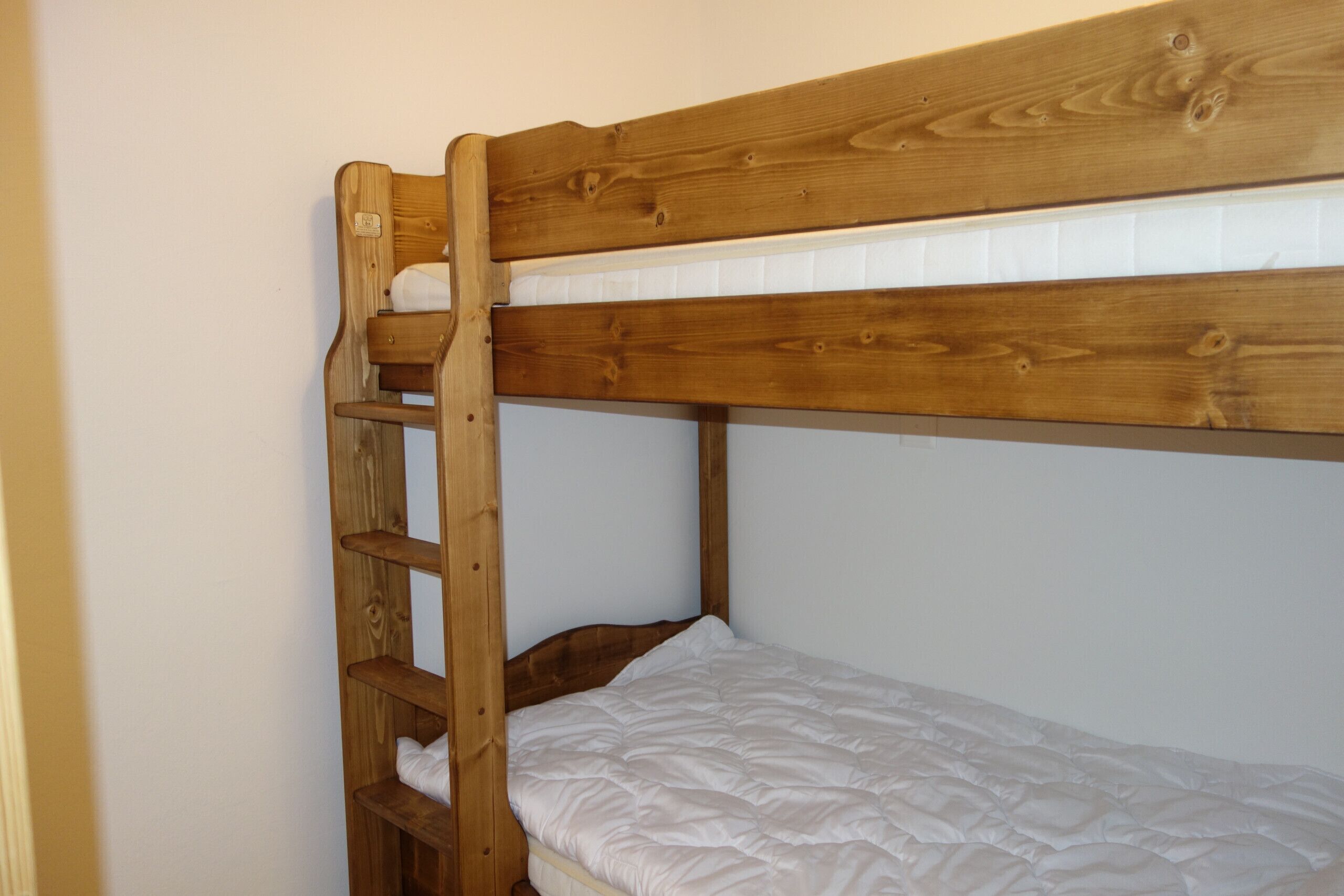 Un lit superposé avec une structure en bois et un matelas blanc.