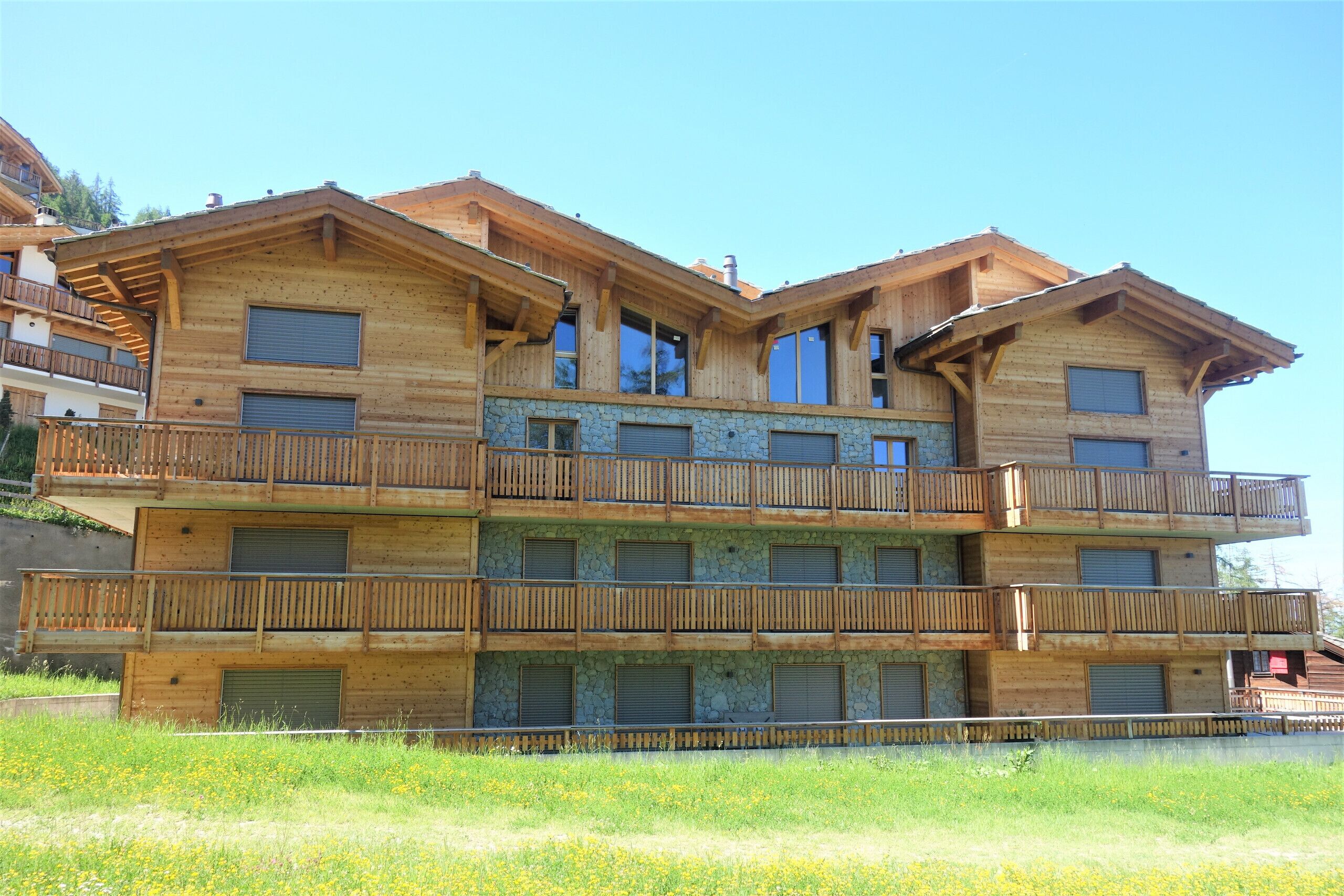 Ein mehrstöckiges Holzgebäude mit Balkonen und großen Fenstern.