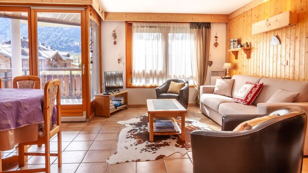 Ein gemütliches Wohnzimmer mit Holzvertäfelung, einer Couch, einem Couchtisch und einem Fernseher.