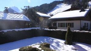 Ein schneebedecktes Gebäude mit geneigtem Dach, umgeben von Schnee und Bäumen.