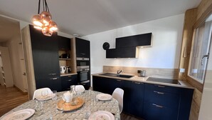 Una cucina moderna con mobili scuri, un piano di lavoro in legno e un'area pranzo con tovaglia fantasia.