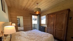 Camera da letto con un letto grande, pareti in legno, termosifone e finestra vista.