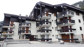Un edificio a più piani con balconi, facciata in pietra e un'area di parcheggio.