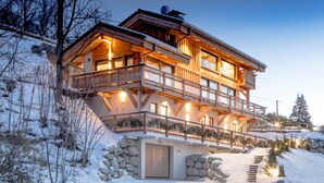 A multi-story chalet with a wooden exterior, balconies, and a stone entrance. - Chalet Caprice, 8 people (COMBLOUX)