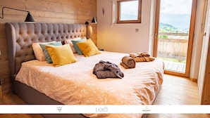 A bedroom with a large bed, multiple pillows, a window, and a view of the outdoors. - Chalet Caprice, 8 people (COMBLOUX)