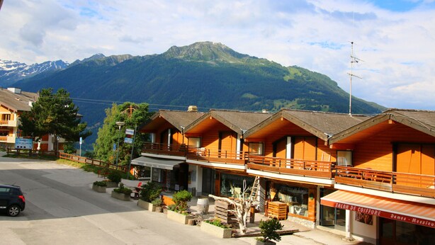 Un chalet de montagne avec des cabanes en bois, un balcon et une vue sur les montagnes.