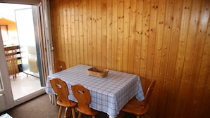 Un coin repas avec une table dressée pour quatre personnes, des chaises en bois et un panier posé sur la table.