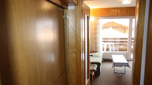 Un couloir intérieur en bois mène à un balcon agrémenté d’une table et de chaises.