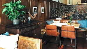 A room with a wooden panel wall, a dining area with a table and chairs, a potted plant, and a decorative metal wall piece. - Hotel Weinhaus Zum Schwarzen Bv Ren (Koblenz)