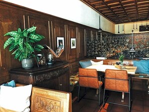 A room with a wooden panel wall, a dining area with a table and chairs, a potted plant, and a decorative metal wall piece. - Hotel Weinhaus Zum Schwarzen Bv Ren (Koblenz)