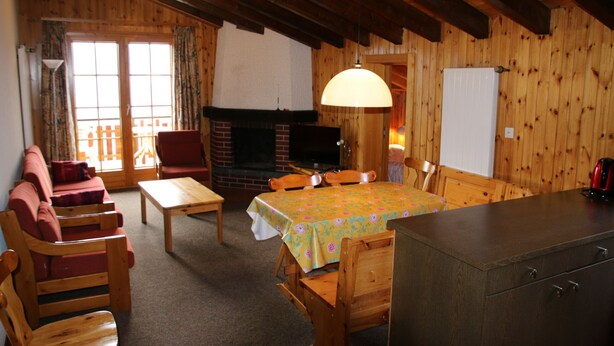 A cozy wooden interior with a sofa, chairs, a table, a fireplace, and a dining area. - Mayens de l'Ours DZ 130 - MOUNTAIN apartment 8 per (Les Agettes)