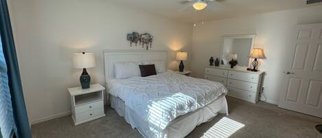 A bedroom with a bed, nightstands, a dresser, a ceiling fan, and a mirror.