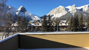 A snow-covered mountain landscape with a chalet-style building in the foreground. - Beautiful Canmore Home with views and walk to DT (Canmore)
